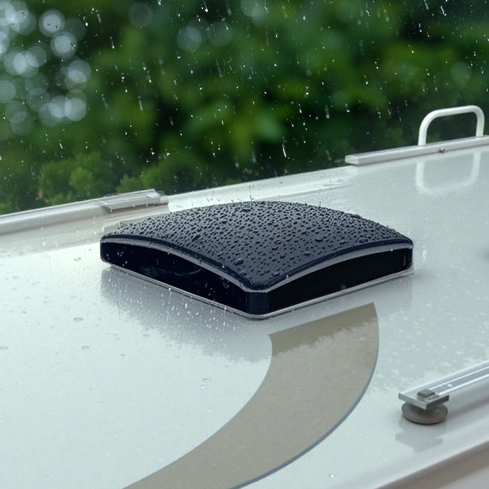 Black sunshade on a caravan window with raindrops, outdoors.