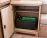Battery inside a wooden cabinet with electrical components in a vehicle or RV setting.