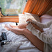 Person sitting on a bed with a remote control, adjusting temperature from a distance.