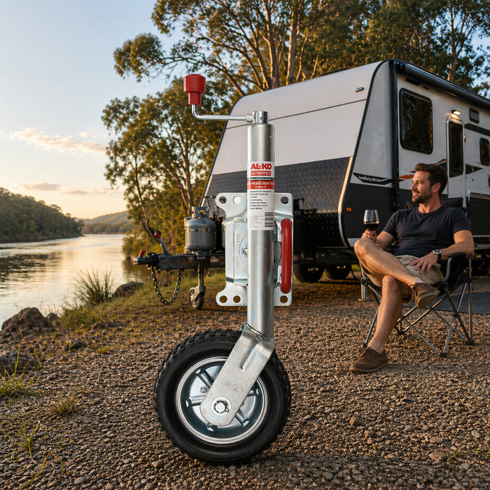 Jockey Wheel in foreground with man sitting by a camper trailer by a lake