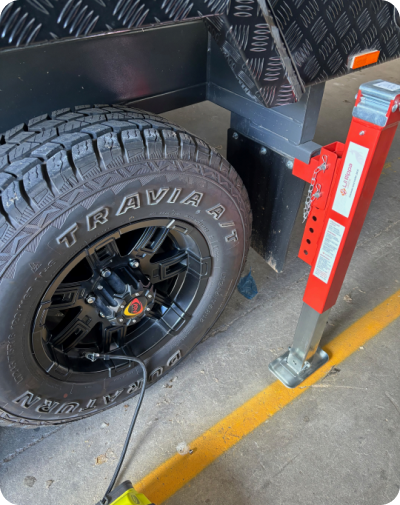 Tire on a vehicle with a red jack attached.