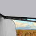 View from inside a vehicle with a roof window open, showing a landscape with trees and sky.