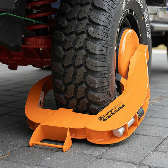 Orange wheel clamp on a vehicle tire on a paved surface