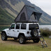 White Jeep Wrangler with a rooftop tent in a mountainous landscape