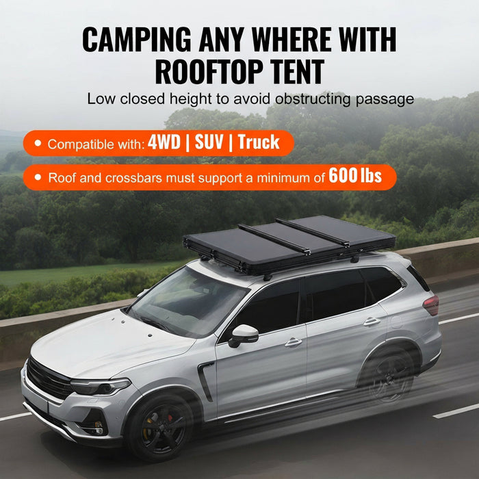 SUV with a rooftop tent on a road with trees in the background